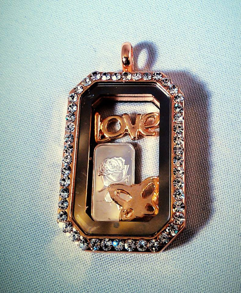 A story locket with rinestones, a stamped silver gram with a rose, love, and butterfly